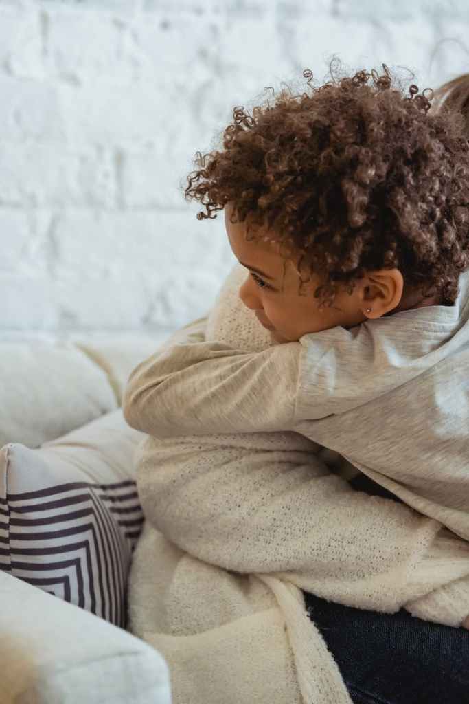 mother hugging with ethnic kid on couch